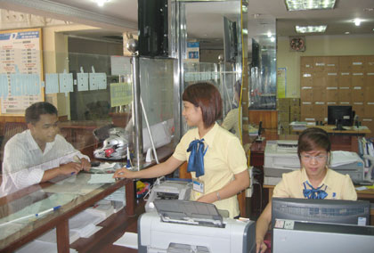 Giao dịch viên hướng dẫn khách hàng sử dụng chuyển tiền tại Bưu cục