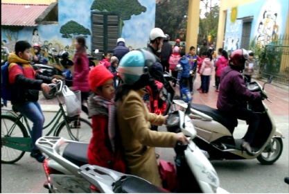 Cần đẩy mạnh công tác tuyên truyền để các bậc phụ huynh thực hiện quy định đội mũ bảo hiểm cho con em khi đến trường (ảnh: Kim Thu).